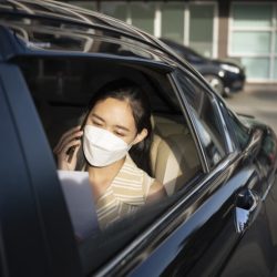 Asian businesswoman talking on mobile phone while sitting on back seat of car.